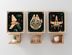 three wooden shelves with artwork on them in the shape of spaceships and space shuttles