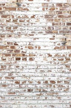 an old brick wall is painted white and brown