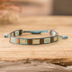 a blue and brown beaded bracelet sitting on top of a wooden table