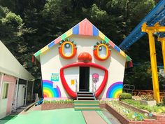 a brightly colored building with a face painted on it's side and stairs leading up to the entrance