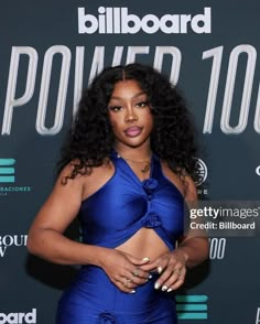 a woman in a blue dress poses on the red carpet at billboard power 100 event