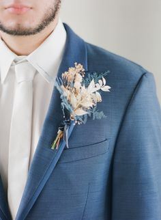 a man in a blue suit with a boutonniere on his lapel