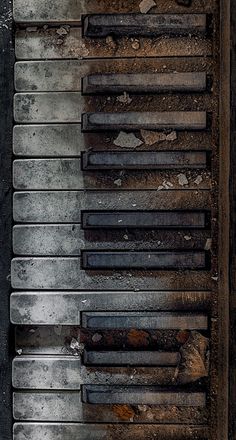 an old piano sitting on top of a wooden floor next to a wall with peeling paint