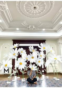 a woman sitting on the floor in front of white flowers