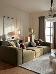 a living room filled with lots of furniture and pillows on top of a wooden floor