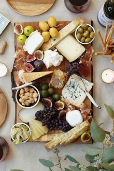 an assortment of cheeses, crackers and olives on a table