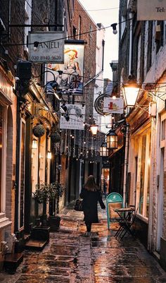 a woman walking down an alley way in the rain