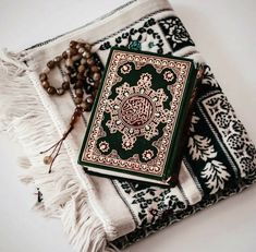 a green and red book sitting on top of a table next to a beaded necklace