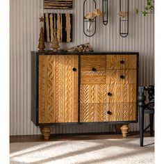 a wooden cabinet with metal handles and knobs on the doors is in front of a striped wall