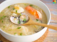 a white bowl filled with soup on top of a wooden table next to a spoon