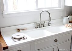 a kitchen sink with two faucets and plates on the counter next to it