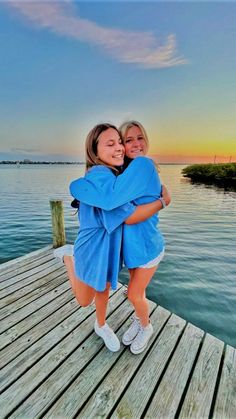 two girls hugging each other on a dock