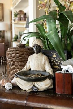 a buddha statue sitting on top of a wooden table next to a potted plant