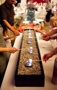 people are standing around a long table with candles on it and the words, 4 have a s'mores bar