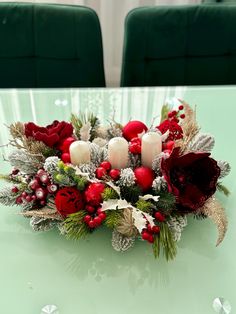 the centerpiece is decorated with candles, holly and red flowers on a green table