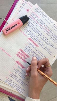 a person writing on a notebook with a pen