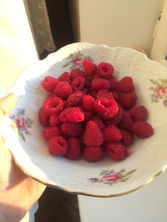 a white bowl filled with raspberries on top of a table