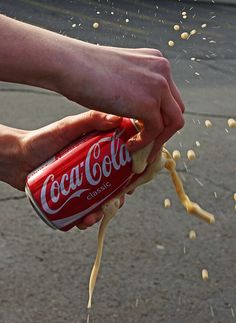 a person is sprinkling some food on the ground with a can of coca - cola