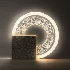 an illuminated object in the shape of a circle with writing on it and a square block next to it