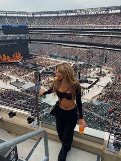 a woman standing on top of a balcony next to a stadium filled with people watching