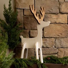 a white deer figurine sitting on top of a wooden shelf next to a brick wall