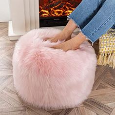 a woman is sitting on a pink bean bag chair in front of a fire place