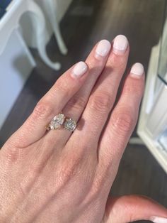 a woman's hand with a diamond ring on top of her finger and the other hand holding an engagement ring