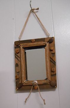 a mirror hanging on the wall with rope around it and an empty piece of wood