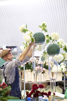 an image of a man arranging flowers in vases on the same day as he looks at them