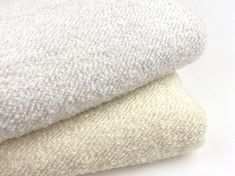 two white towels stacked on top of each other in front of a white background,