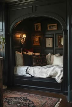 a bed sitting in the corner of a room next to a rug and wall with pictures on it