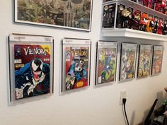 several comics are hanging on the wall next to each other in a room with shelves full of comic books