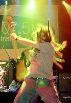 a man with long hair playing guitar on stage