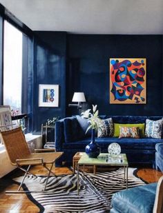 a living room filled with blue couches and zebra print on the floor next to large windows