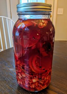 a jar filled with red liquid sitting on top of a wooden table