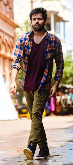 a man walking down the street with his foot in the air while wearing a plaid shirt and khaki pants