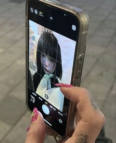 a woman holding up her cell phone to take a selfie with the camera in front of her