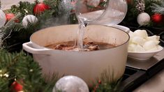 a pot filled with hot chocolate sitting on top of a stove next to christmas decorations