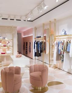 the inside of a clothing store with pink chairs and gold accents