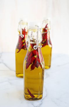 three glass bottles filled with flowers on top of a marble countertop next to each other