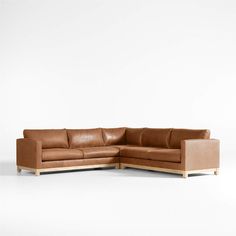 a brown leather sectional sofa sitting on top of a white floor next to a wooden frame