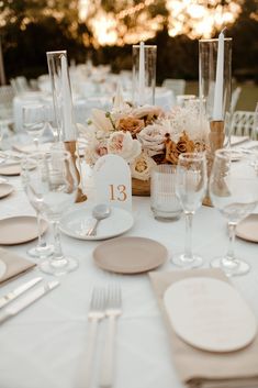 the table is set with white plates and place settings for guests to sit down at