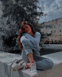 a woman sitting on the edge of a wall with her head resting on her hands