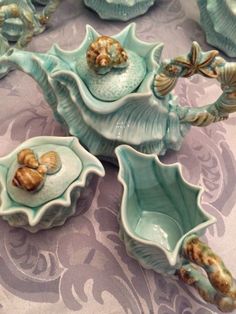 there are many blue dishes on the table with sea shells in them and seashells