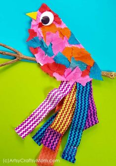 a colorful paper bird sitting on top of a branch