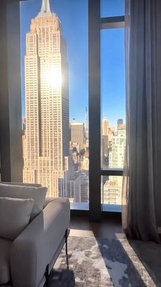 a living room with a couch, chair and large window overlooking the empire state building