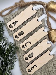 three wooden name tags hanging from a string on top of a knitted bag next to christmas decorations