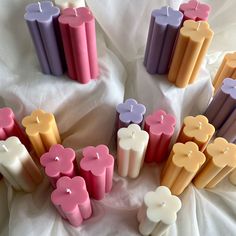 many different colored candles are arranged on a white sheet with one candle in the middle