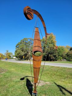 a wooden sculpture in the middle of a grassy area with trees and blue sky behind it