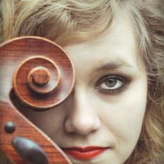 a woman holding a violin in front of her face